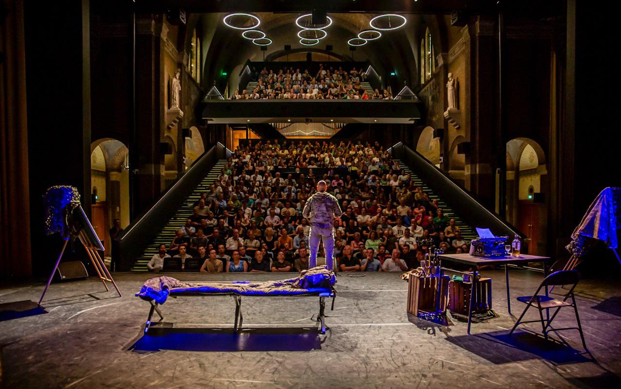 Spreker op het podium voor een volle zaal